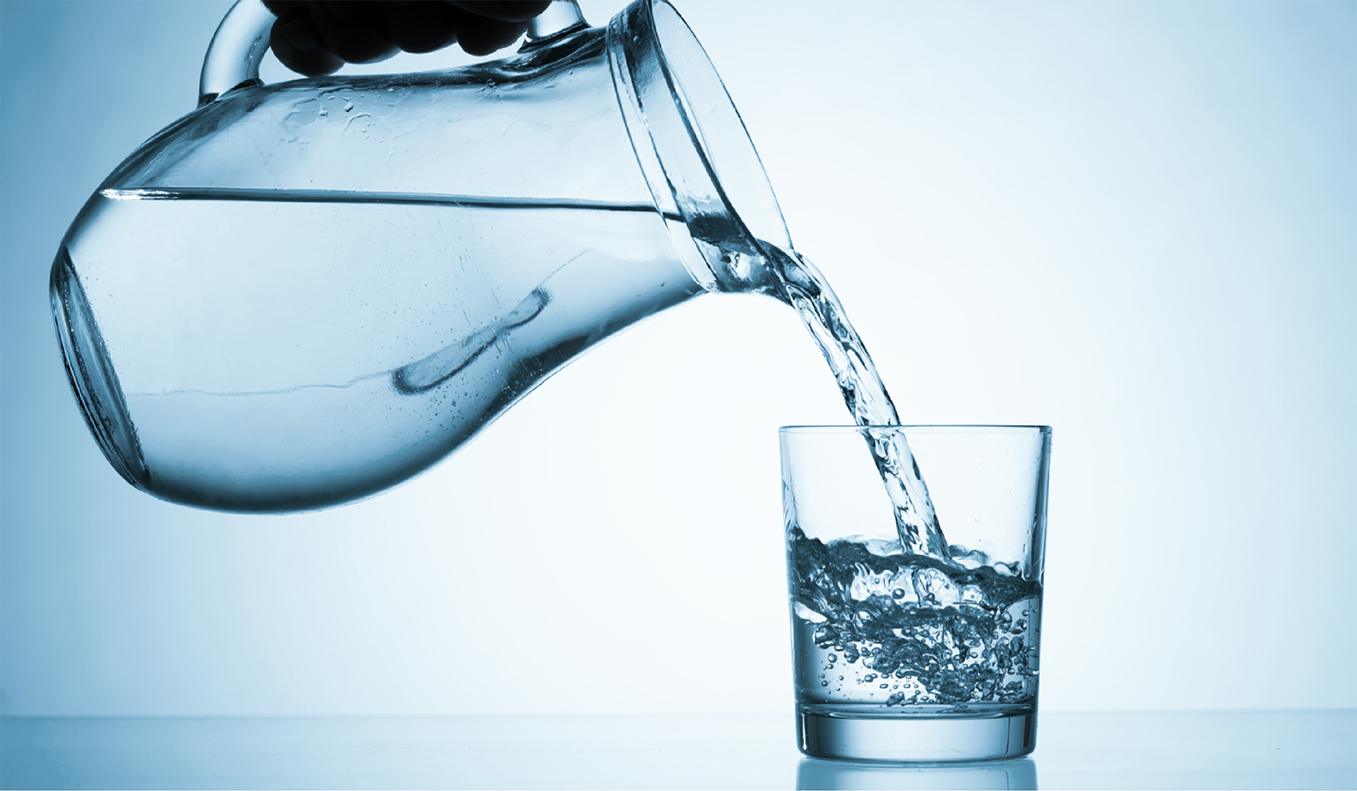 pitcher of clear quality water being poured into glass after effective water treatment