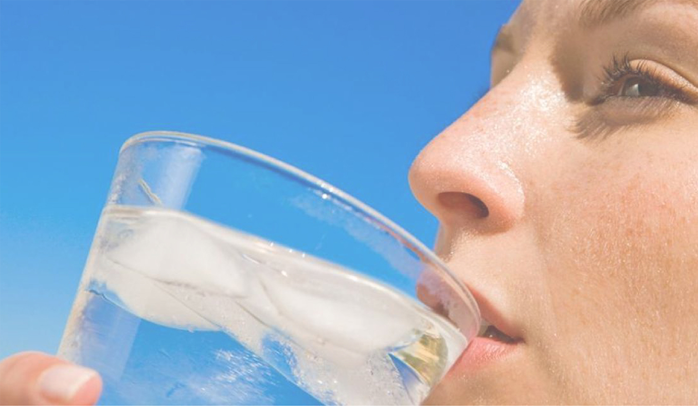 Lady drinking from glass of clean, clear water