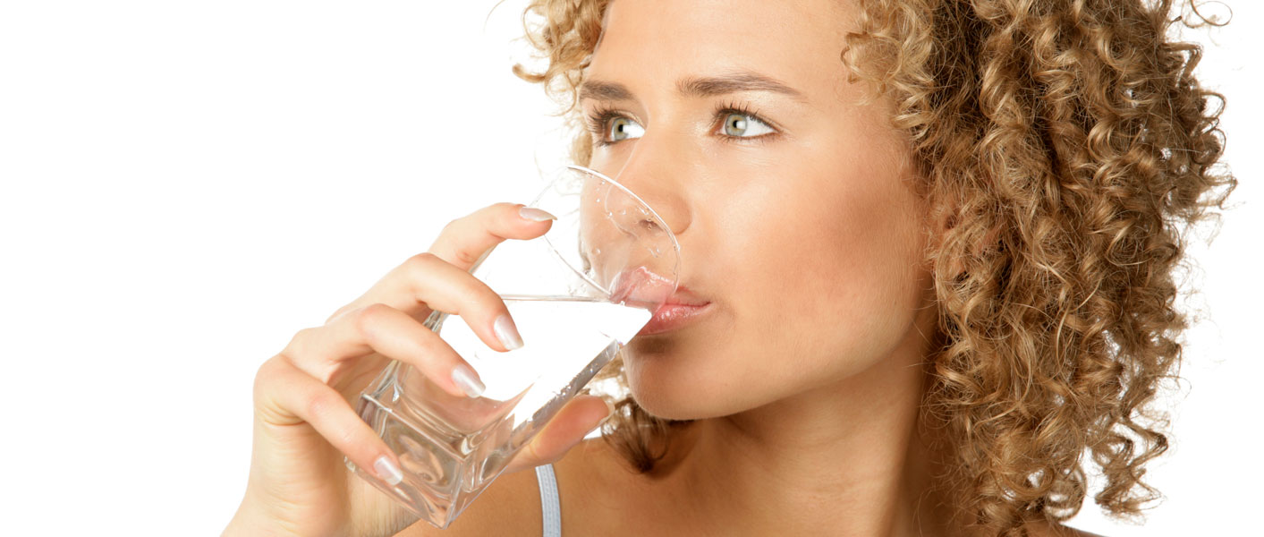Woman drinking from a glass of clean, clear water after treatment